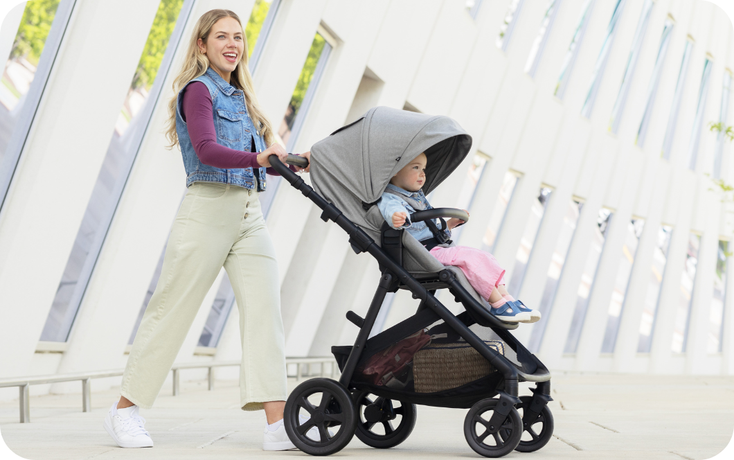 Maman souriante poussant son enfant dans la poussette Graco Near2Me DLX