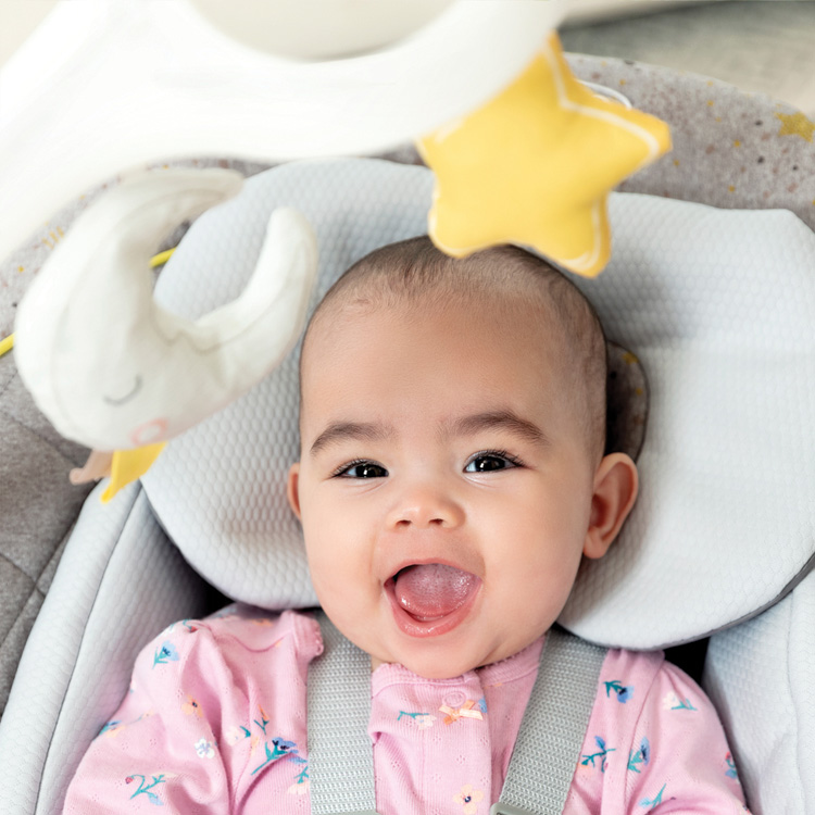 Baby sitzt in der elektrischen Babyschaukel Graco All Ways Soother und schaut auf die Spielzeuge am Mobile