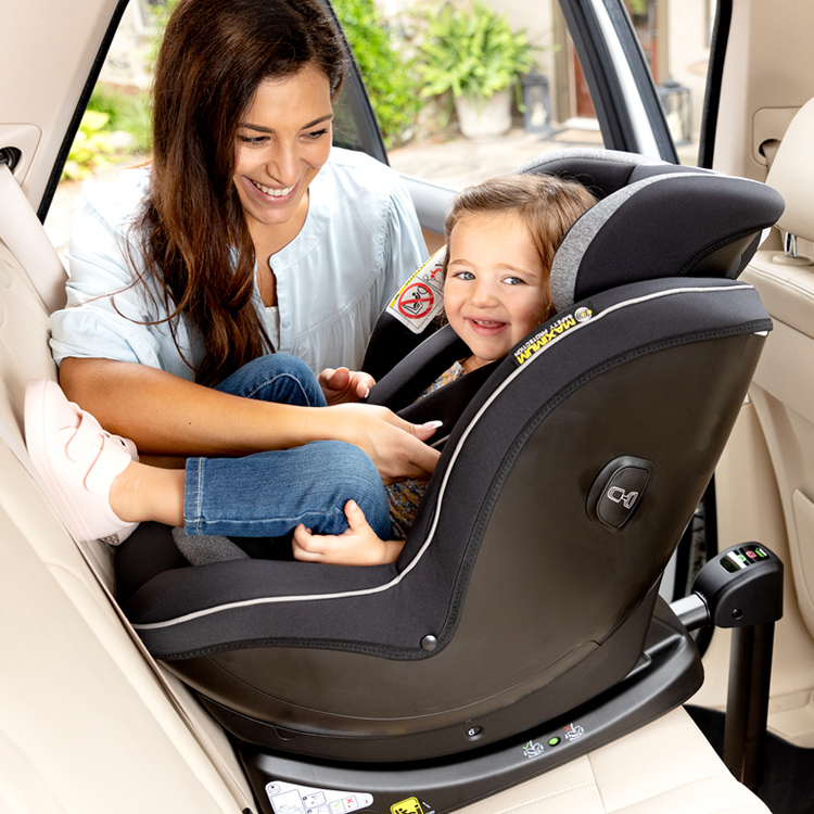 Madre ajustando el arnés del niño sentado en la silla de coche Graco Ascent