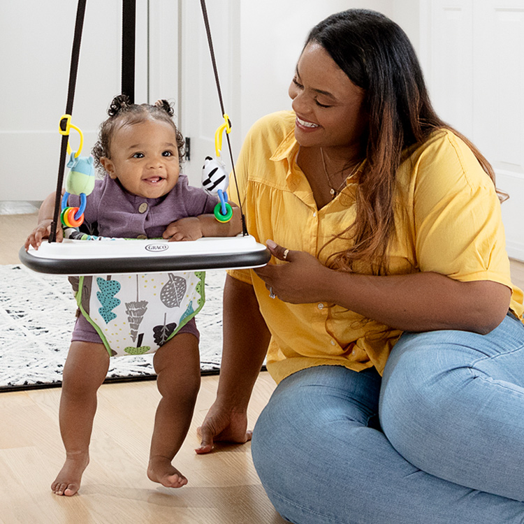 Mutter schaut Baby beim Spielen im Türhopser Graco Bumper Jumper zu