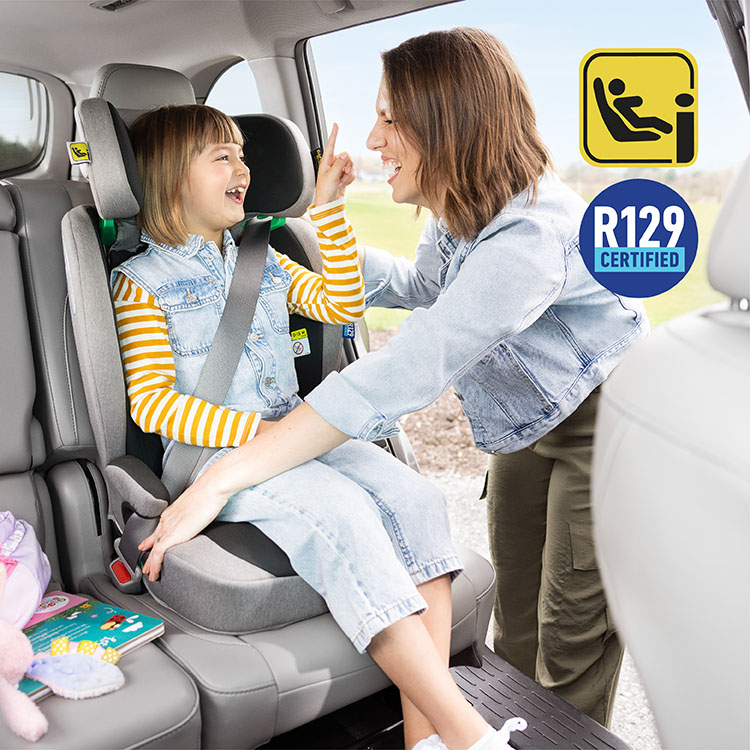 Mum buckling young girl in to Energi i-Size R129 while laughing with i-Size and R129 logos