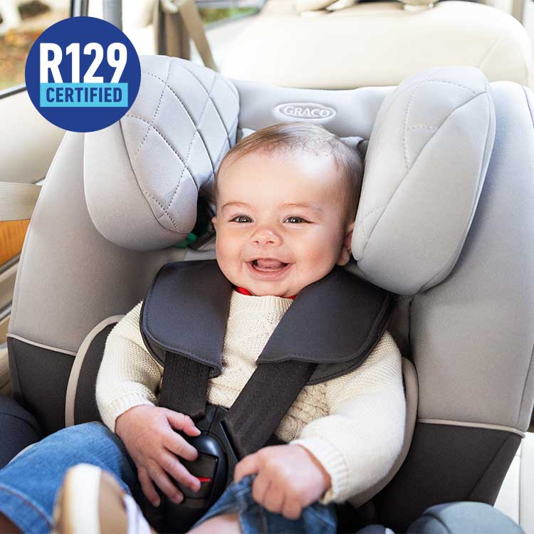 Baby rearward facing in Graco SlimFit R129 2-in-1 convertible car seat with R129 logo.