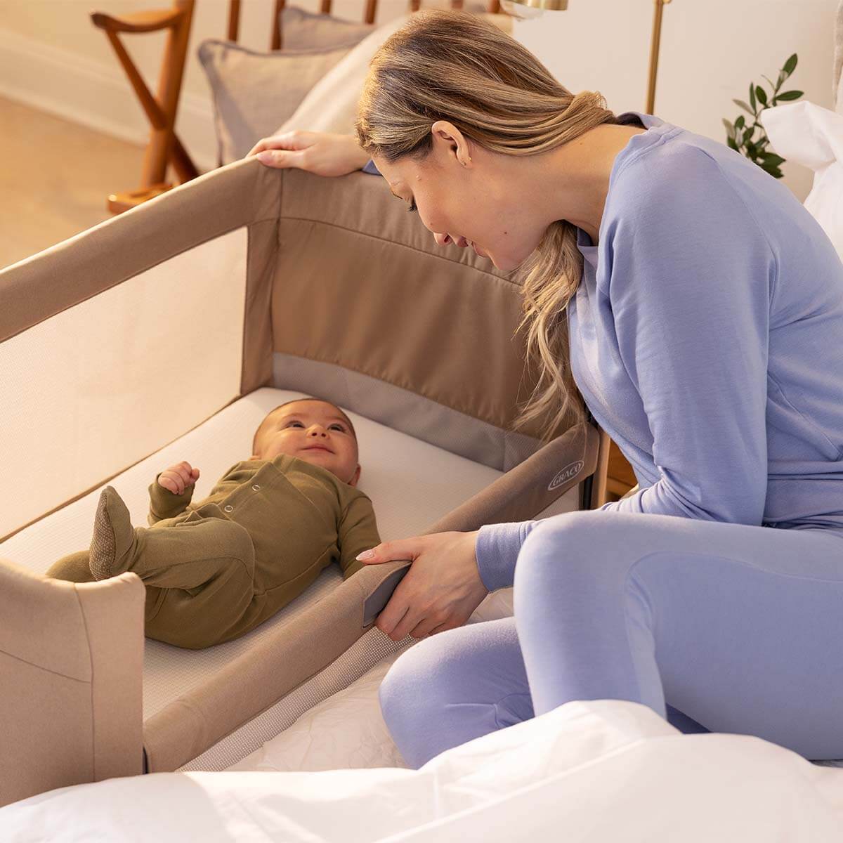 Mamma che abbassa la sponda laterale di Graco Sweet2Sleep per prendere facilmente in braccio il bambino.