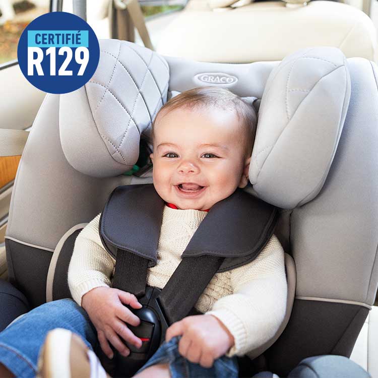 Bébé assis en position dos à la route dans le siège auto convertible Graco SlimFit R129 2-en-1 avec le logo R129.
