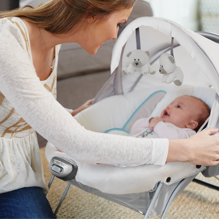 Frau spielt mit ihrem Baby in der elektrischen Babyschaukel Graco Glider Elite