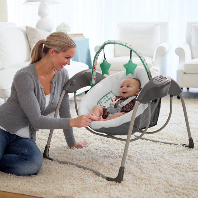 Frau spielt mit ihrem Baby in der elektrischen Babyschaukel Graco Glider Lite