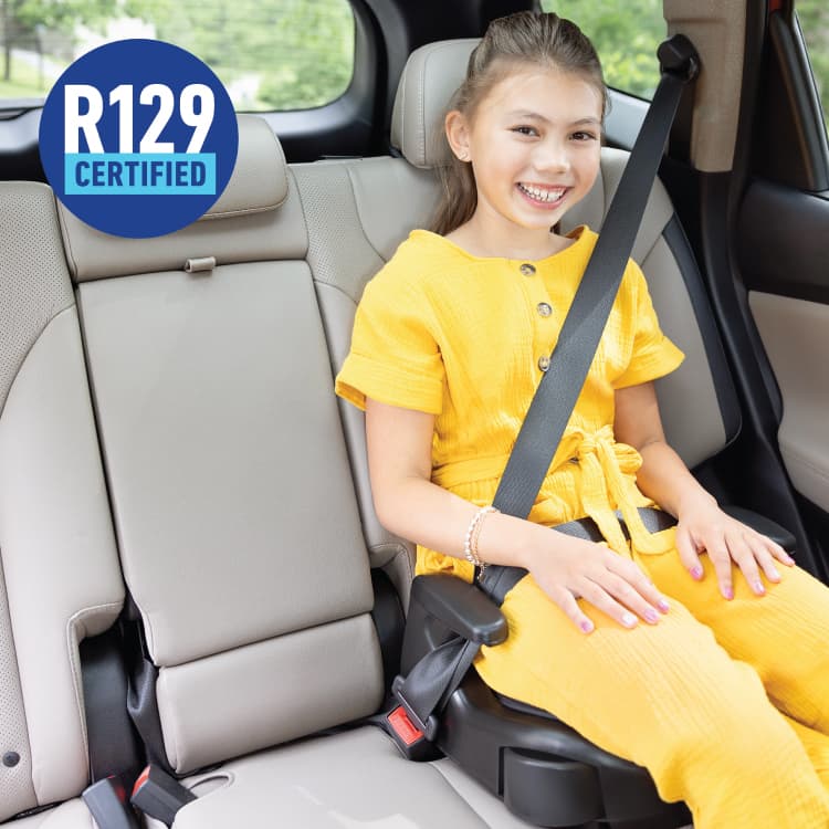 Young girl smiling and sitting in Graco Booster Basic R129 backless booster with R129 logo. 