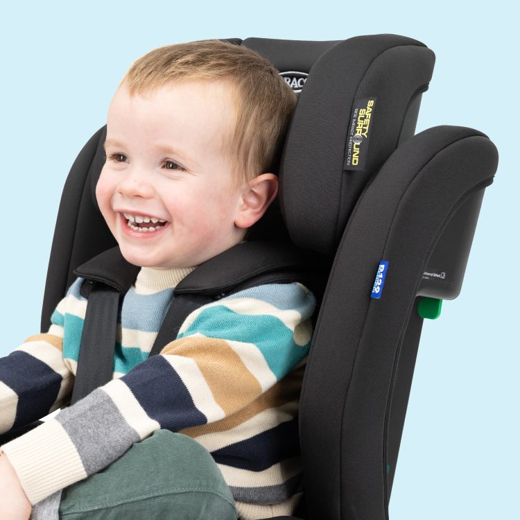 Bambino seduto e sorridente a bordo di Graco Eldura R129 in modalità con cintura integrata con etichetta di protezione dagli impatti laterali Safety Surround™
