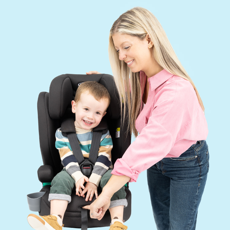 Kleiner Junge sitzt lächelnd im Graco® Eldura™ R129 während seine Mutter das integrierte 5-Punkt-Gurtsystem für ihn einstellt.
