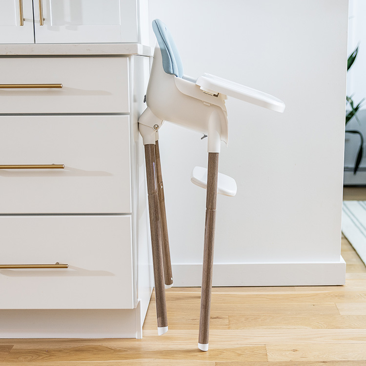 Profile shot of Graco Presti 3-in-1 highchair neatly folded and tucked into a corner in a kitchen.