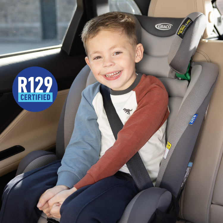 Little boy buckled in Graco FlexiGrow™ R129 2-in-1 harness booster and laughing with R129 certified logo
