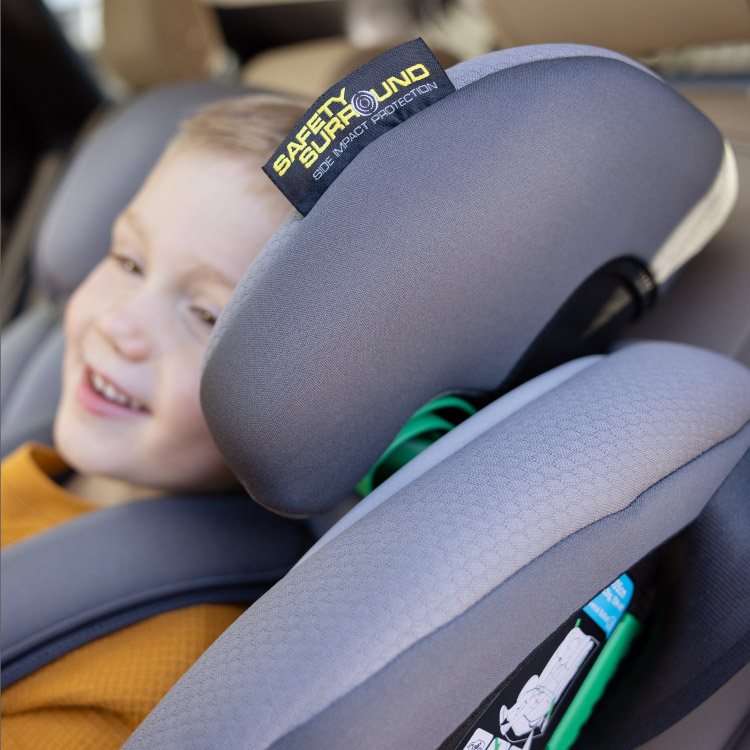 Little boy sitting and smiling in Graco FlexiGrow™ R129 2-in-1 harness booster car seat featuring the Safety Surround™ Side Impact Protection tag
