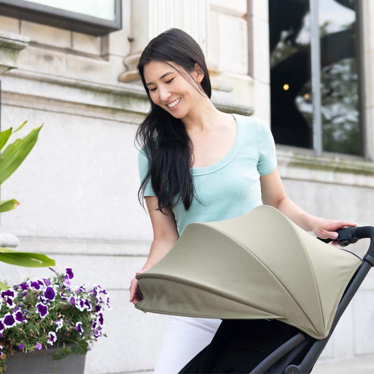 Famiglia felice che cammina con i bagagli e il bambino nel passeggino Graco myavo.