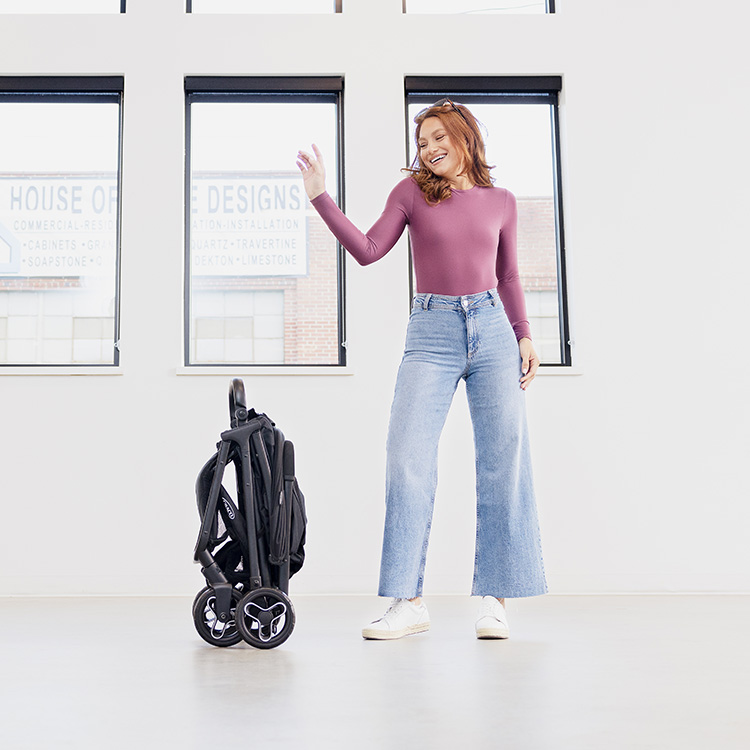 Mutter lächelt und faltet den leichten Graco® Myavo™ Reisebuggy zusammen
