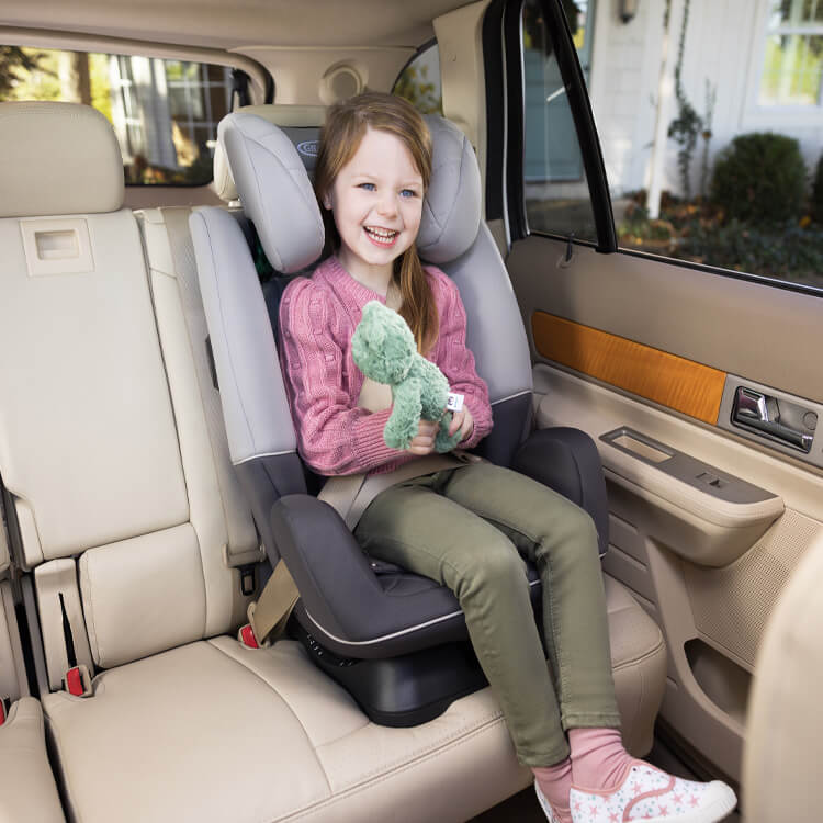Big kid sitting in Graco SlimFit R129 2-in-1 convertible car seat in highback booster mode. 