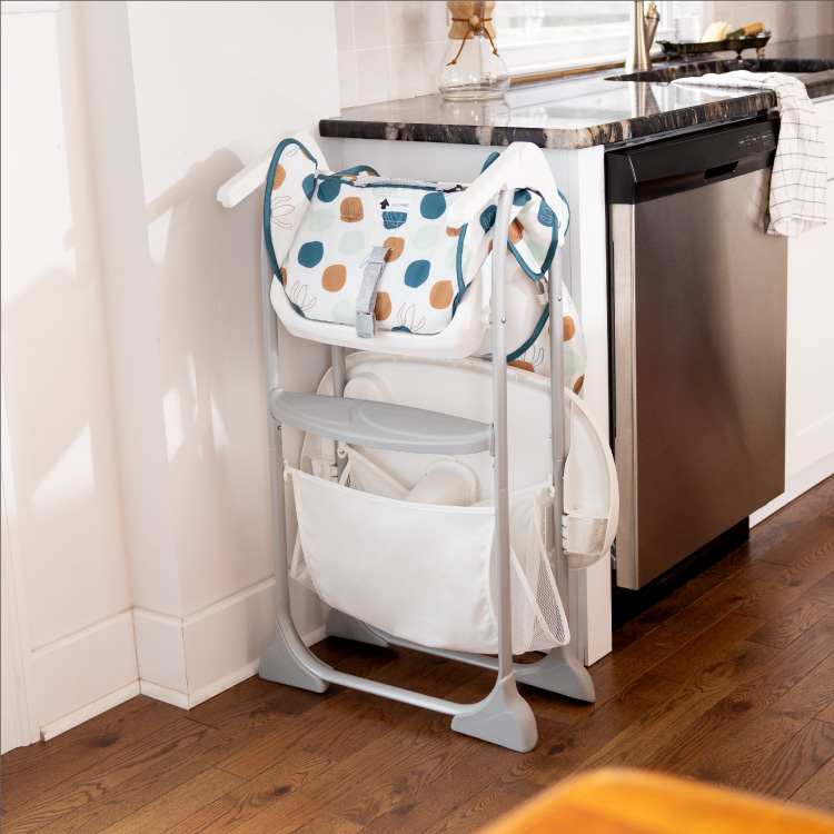 Graco SnackEase highchair folded compactly and standing up on its own next to the kitchen counter.
