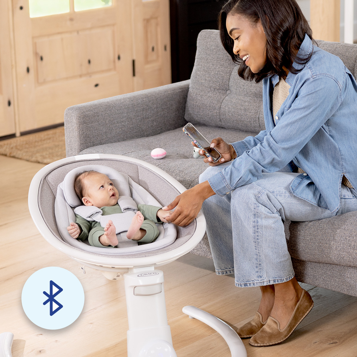 Mum connecting her phone via Blueooth to Sway 'n Grow 3-in-1 silent swing with infant in the swing 
