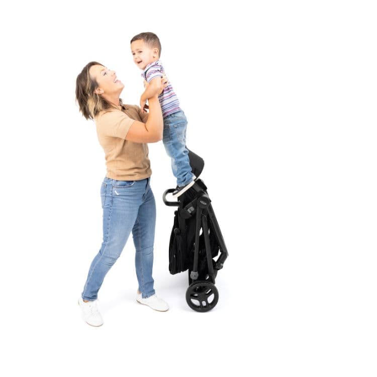 Mum holding her child while Graco Transform pushchair is folded and self standing