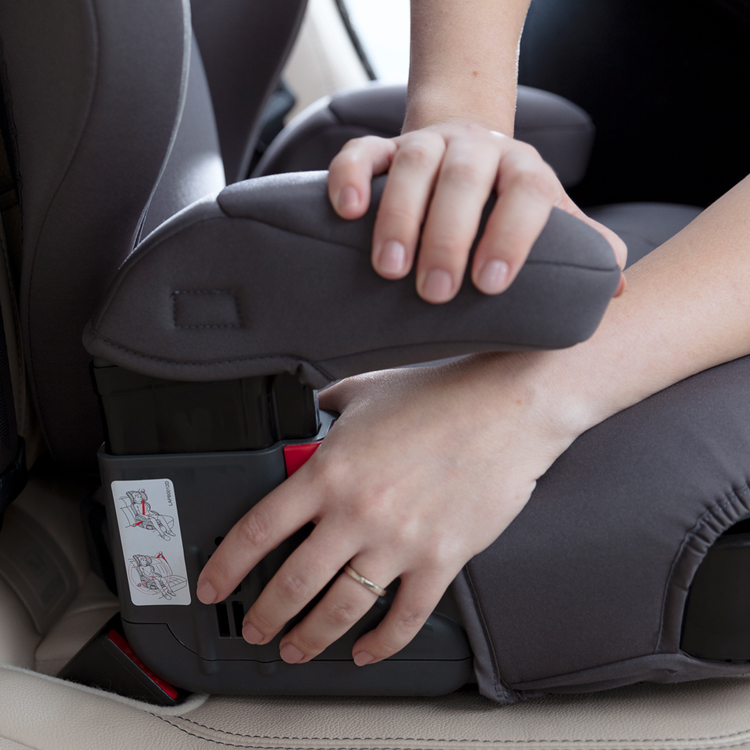 A person adjusting the armrest of the Graco Logico L car seat