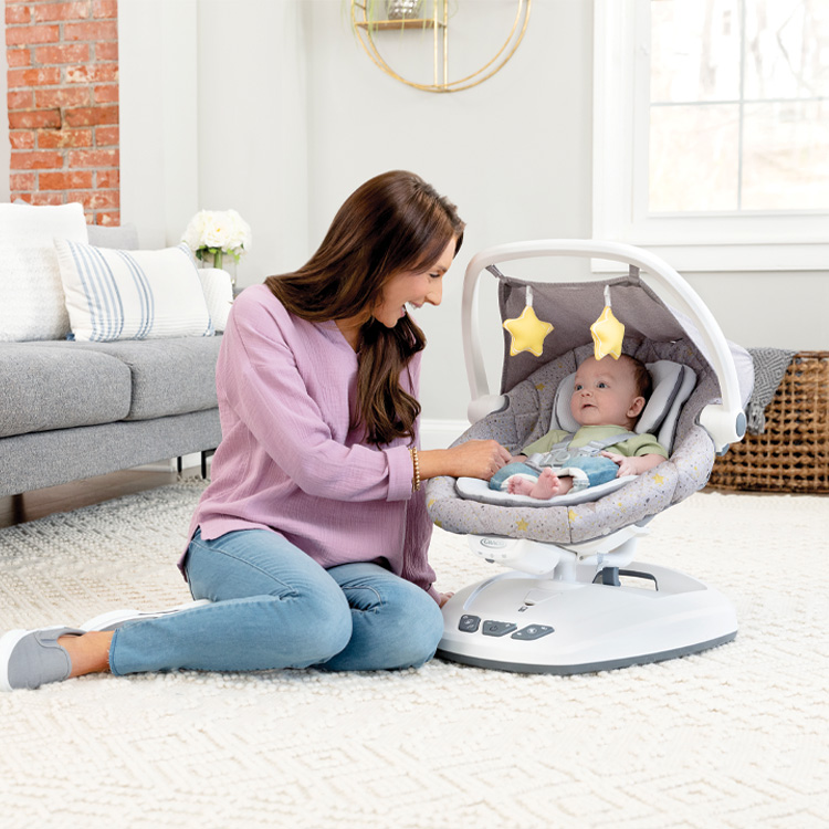 Mum playing with baby sitting in Graco Move with Me soother.