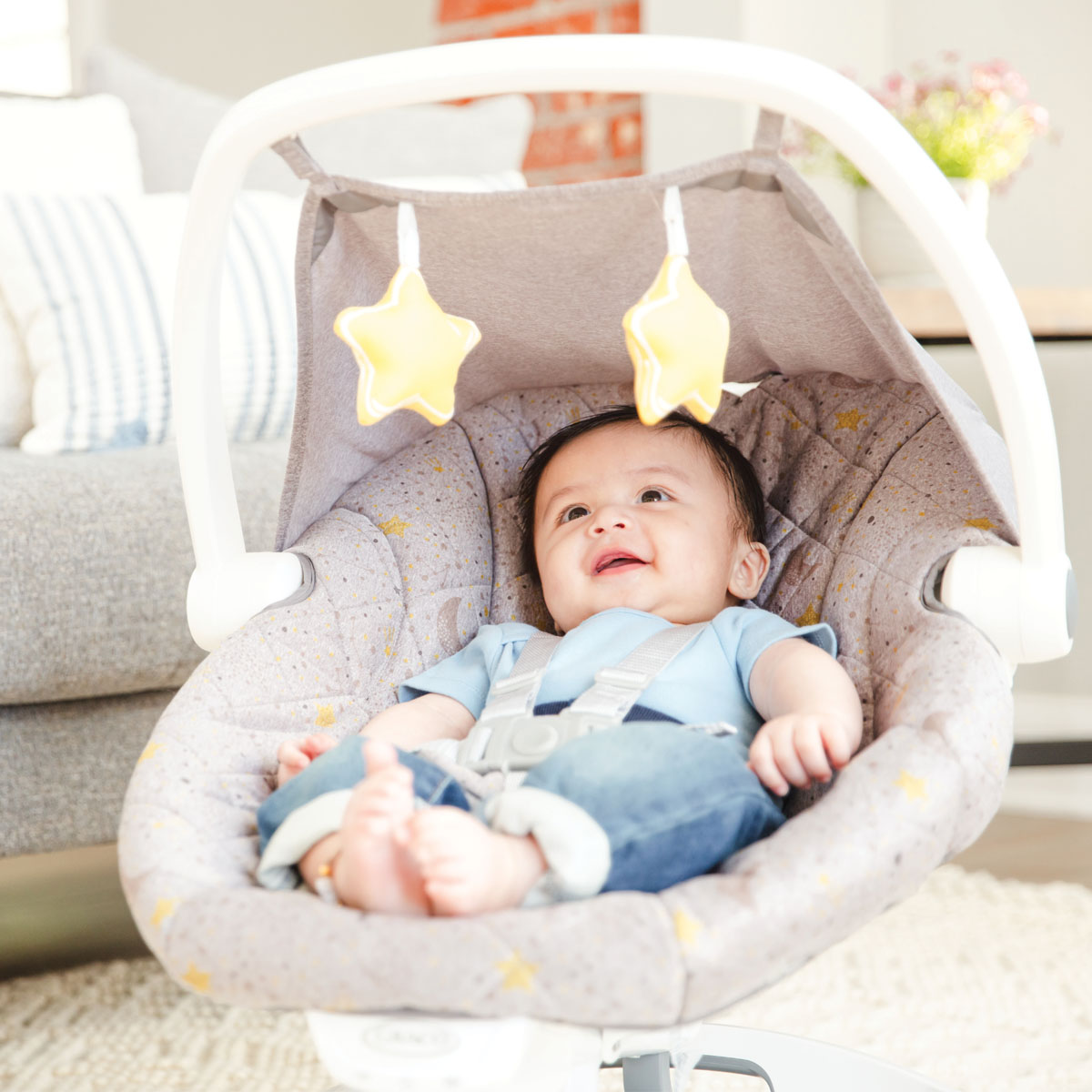 Baby relaxing in Graco Move with Me and looking at the hanging toys