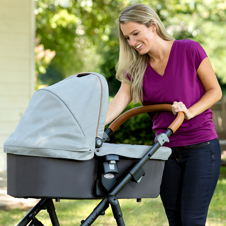 Mutter interagiert mit ihrem Baby in der Babywanne Graco Near2Me, während diese am Kinderwagen Graco Near2Me angebracht ist