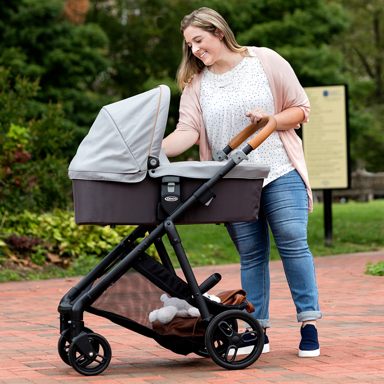 Mum interacting with baby riding in Graco Near2Me™ carrycot while it is attached to Graco Near2Me™ pushchair