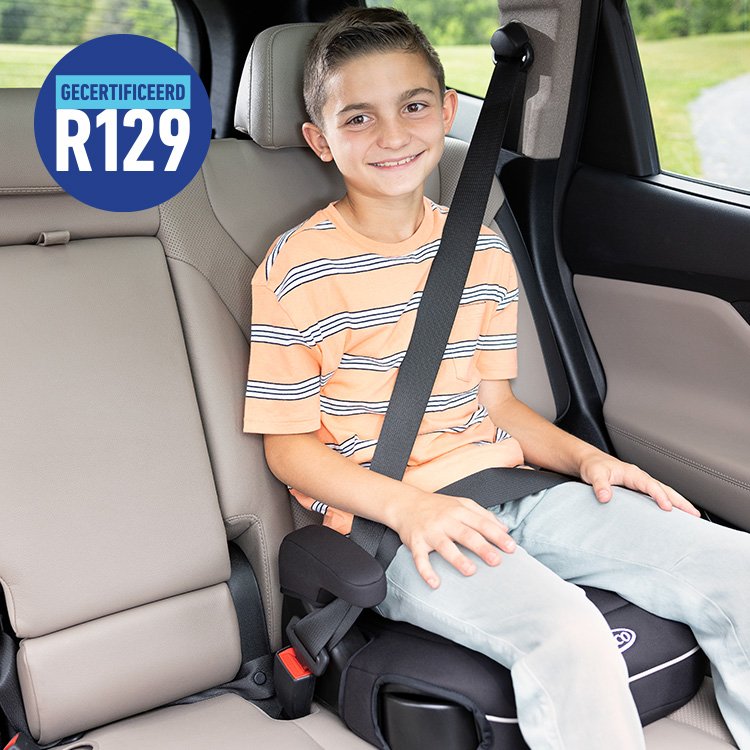 Zittend en lachend jongetje in rugloze Graco Booster Deluxe R129 autostoelverhoger