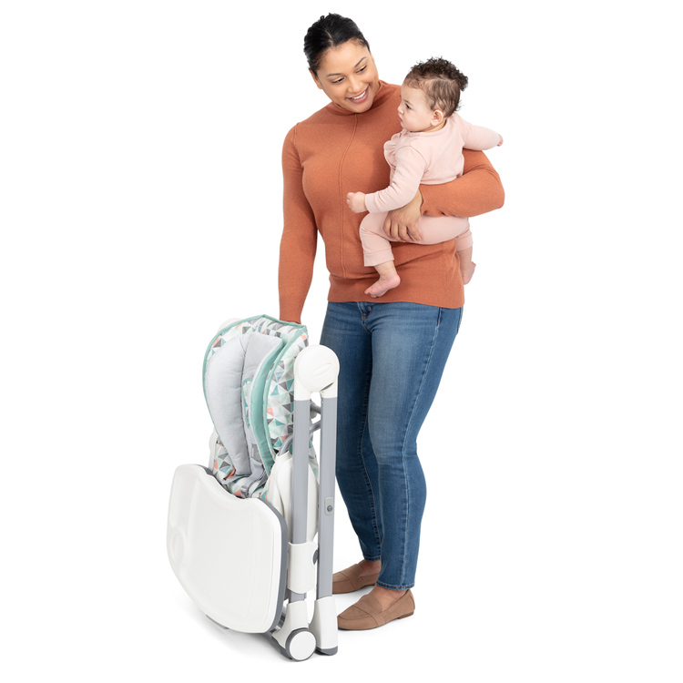 Mum holding her baby in one hand while she folds Graco's Swift Fold with the other hand
