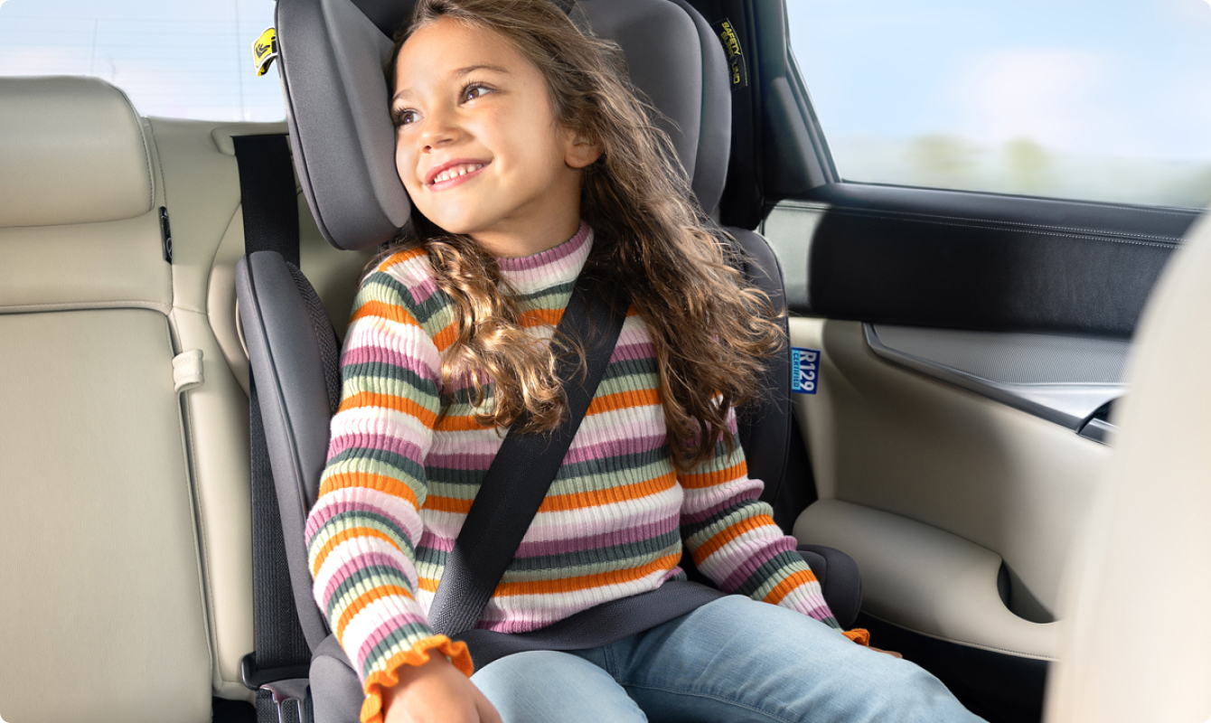 Girl smiling while buckled into Affix i-Size R129 ISOFIX highback booster car seat