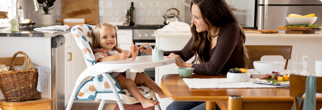 Mum interacting with little girl fastened into SnackEase quick-folding highchair.