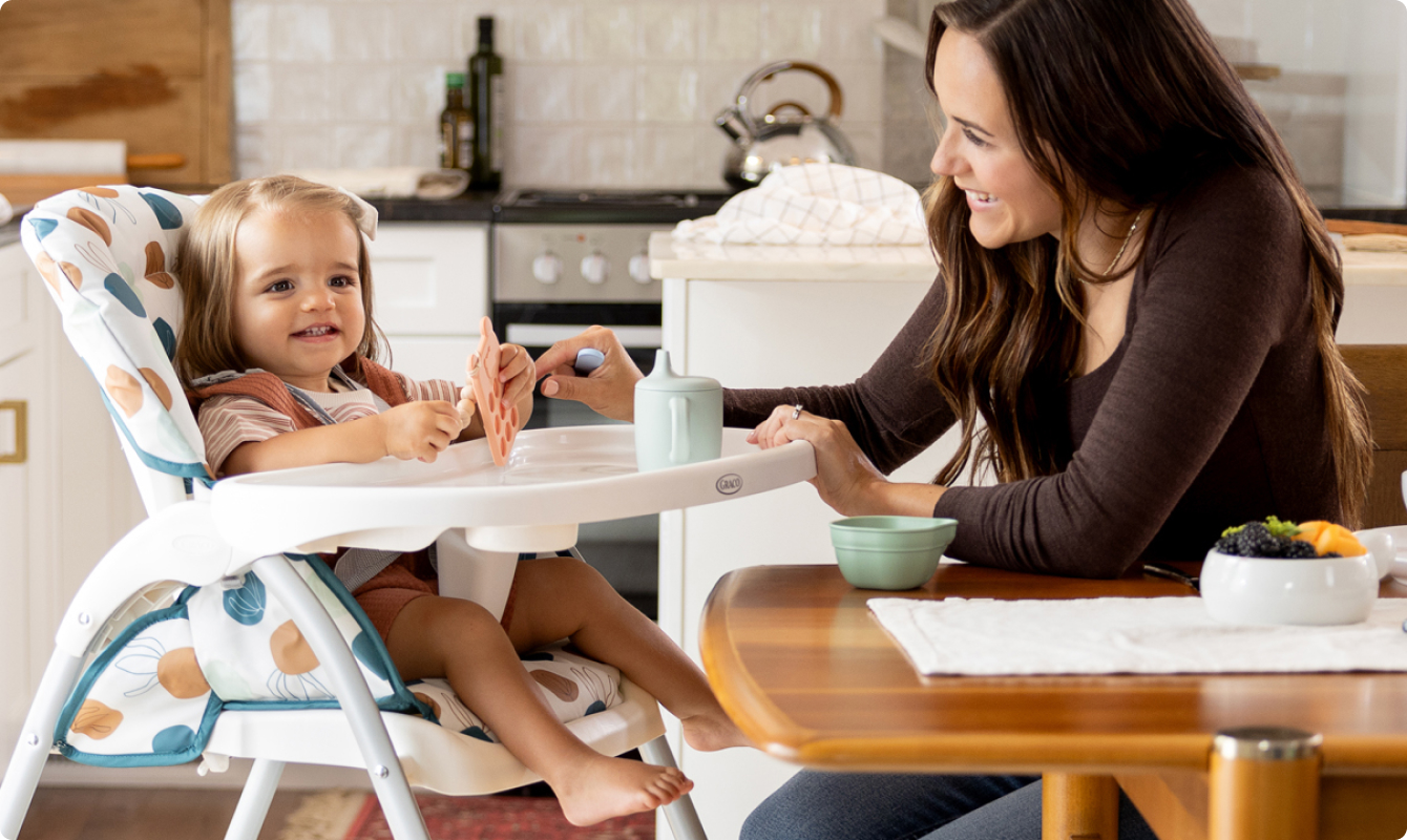 Mum interacting with little girl fastened into SnackEase quick-folding highchair.