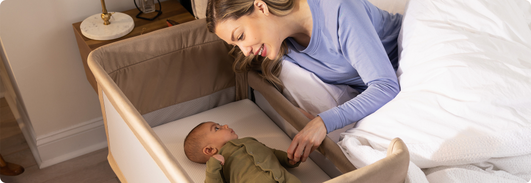 Mum in bed and interacting with infant in Sweet2Sleep bedside crib.