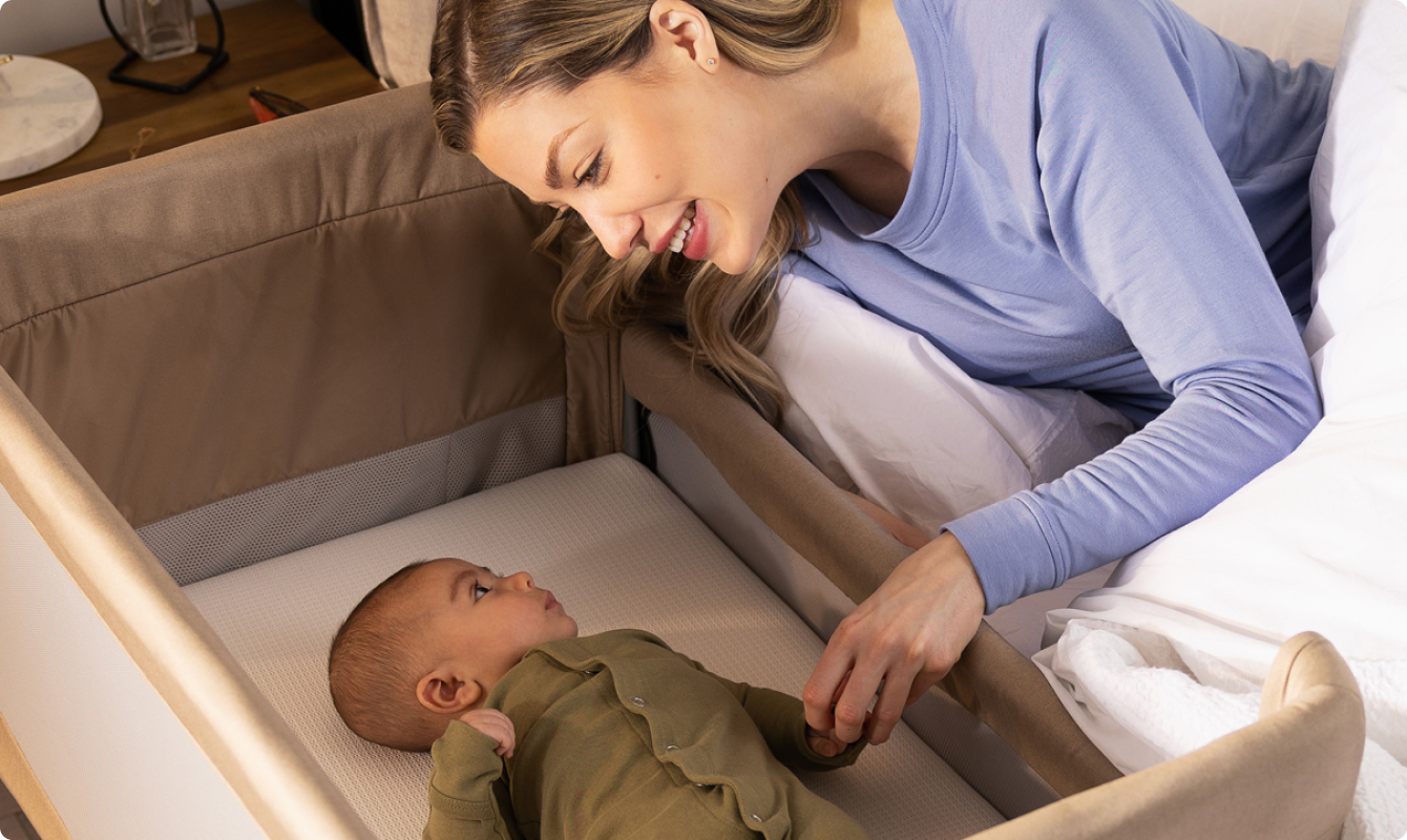 Mum in bed and interacting with infant in Sweet2Sleep bedside crib.