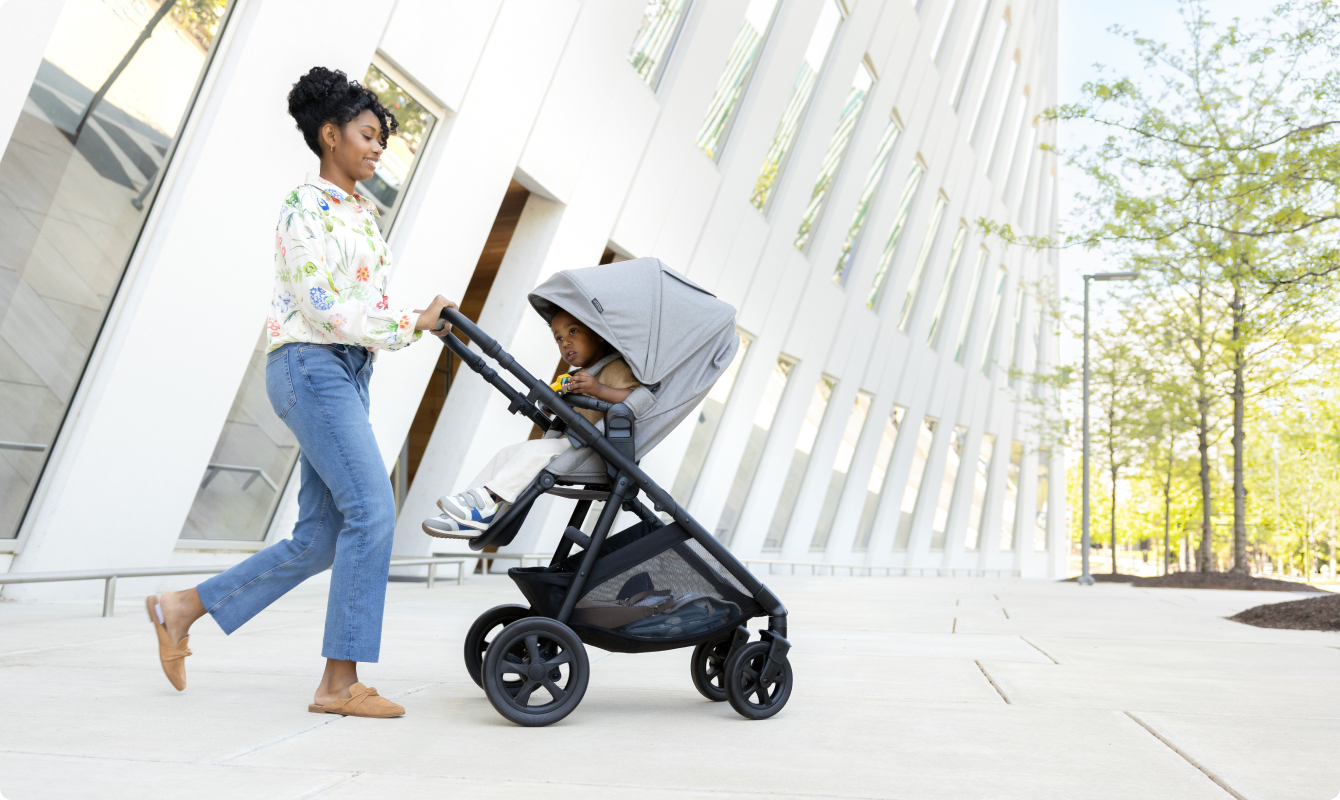 Mum smiling and pushing happy toddler in Near2Me DLX Trio pushchair.