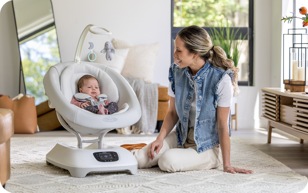 Mom interacting with baby girl buckled into Sway &rsquo;n Grow 3-in-1 silent swing