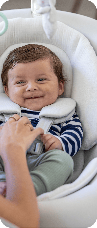 Little girl smiling while buckled into SnackEase quick-folding highchair.