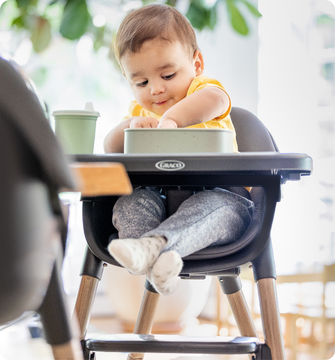 Little girl smiling while buckled into SnackEase quick-folding highchair.