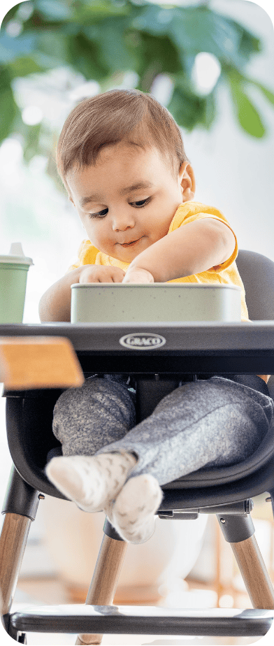 Little girl smiling while buckled into SnackEase quick-folding highchair.