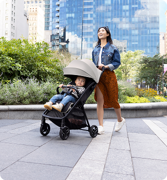 Mum and dad smiling and walking while pushing toddler in Myavo quick-folding lightweight travel stroller.