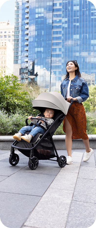 Mum and dad smiling and walking while pushing toddler in Myavo quick-folding lightweight travel stroller.